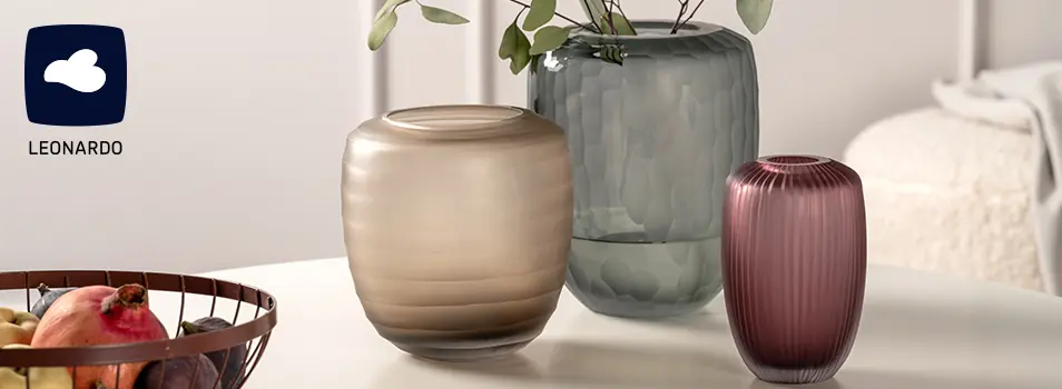 Floreros de vidrio LEONARDO en tonos beige, gris y vino sobre una mesa blanca
